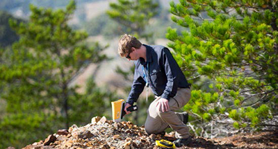 工作人员在野外使用Vanta XRF分析仪勘察岩石的类型和蚀变情况。